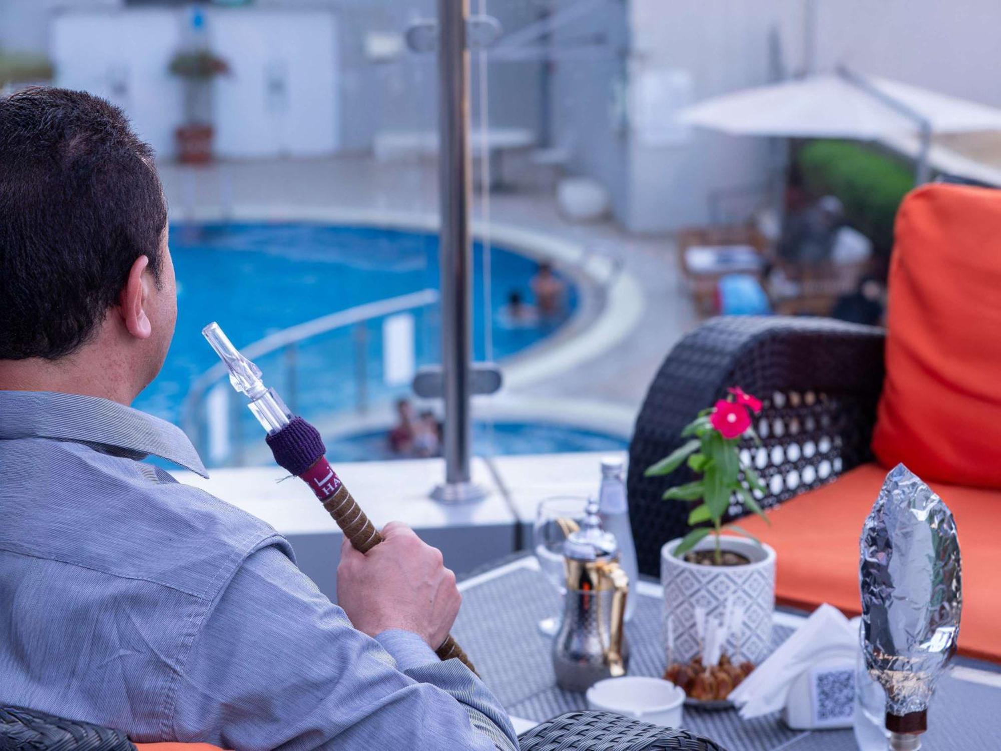 Novotel Jazan Exterior photo A man smokes a hookah in Cairo, Egypt